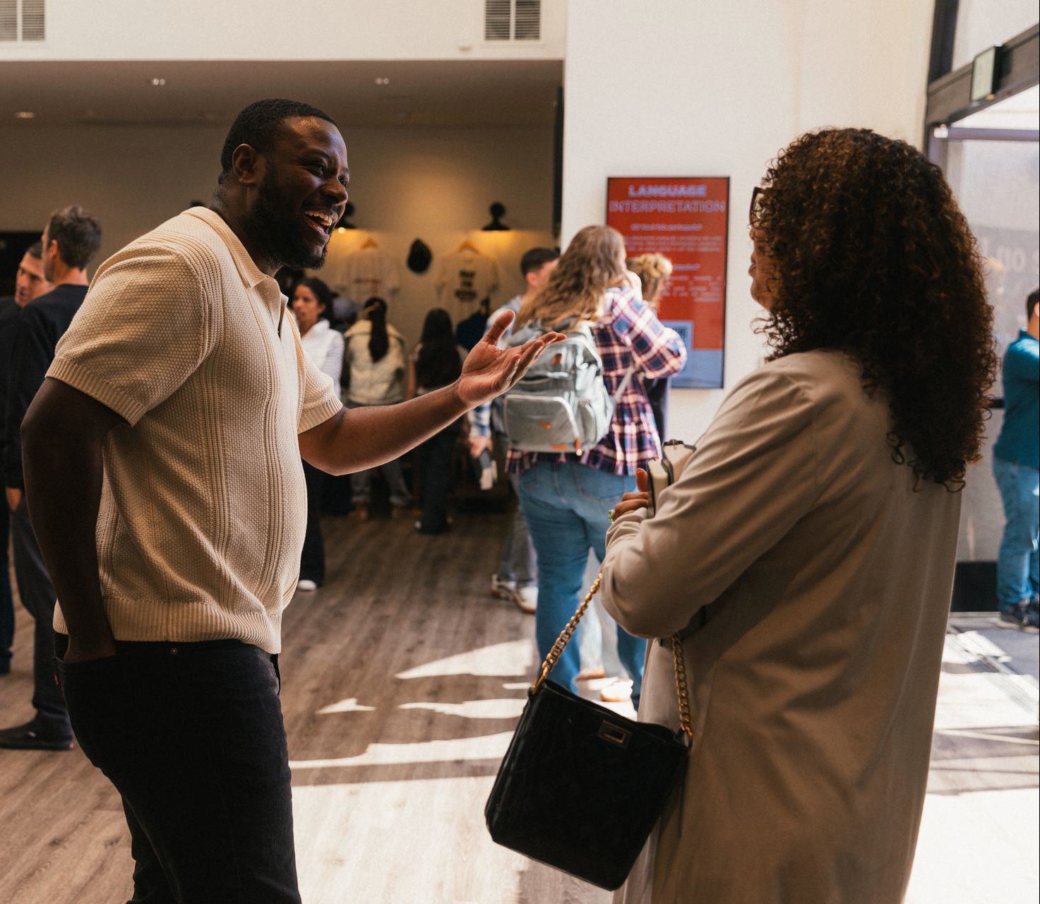 A smiling man warmly greets a woman in a busy church lobby