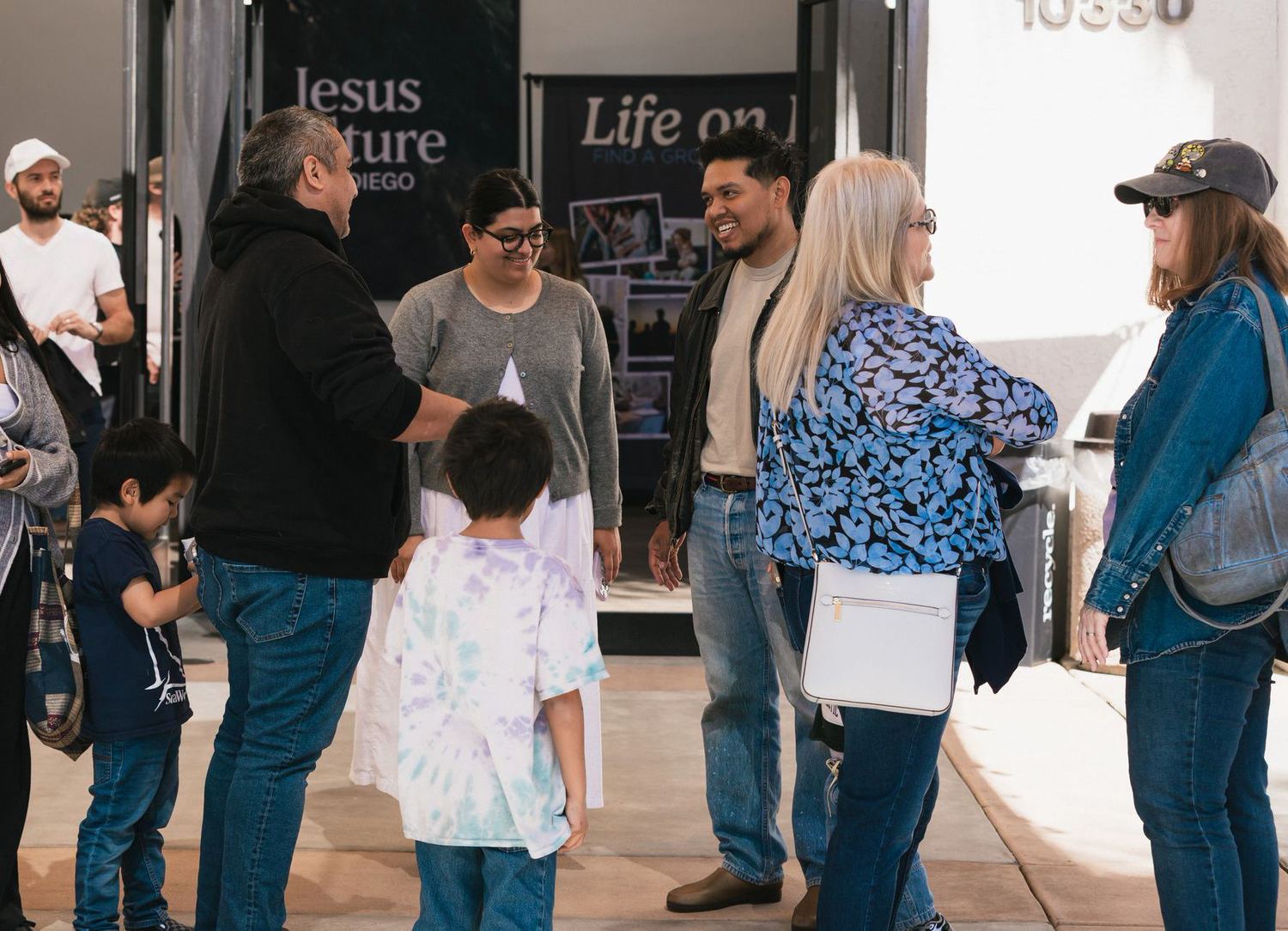 Families and newcomers greeting each other at a church entrance on Sunday